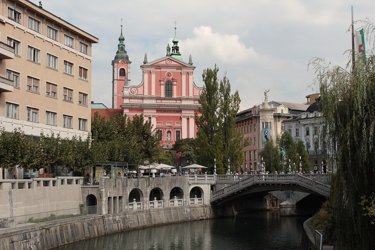 Potrójny most i plac Preseren od strony rzeki Lublany, Lublana, Słowenia” /><figcaption>Zdjęcie: Valerio2468, CC BY-SA 4.0, za pośrednictwem Wikimedia Commons.</figcaption></figure>
<p><span class=